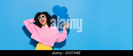 Begeisterte afroamerikanische Frau in modischer Kleidung mit Gedankenblase auf blauem Banner Stockfoto