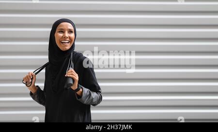 Fröhliche Junge Muslimische Frau In Modest Sportswear, Die Mit Springseil Im Freien Posiert Stockfoto