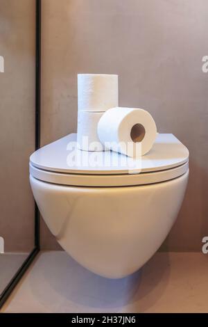 Toilettenpapier. Drei weiße Servietten aus Hygienetuch auf einem hängenden Toilettenschüssel-Deckel gestapelt. Moderne Inneneinrichtung im Bad Stockfoto