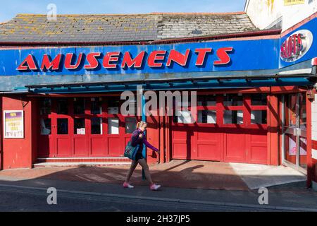 Ein Fußgänger, der in der Nebensaison in Newquay in Cornwall an einer geschlossenen Spielhalle vorbeiläuft. Stockfoto