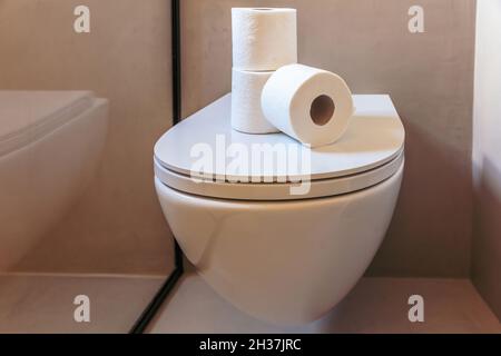 Toilettenpapier. Drei weiße Servietten aus Hygienetuch auf einem hängenden Toilettenschüssel-Deckel gestapelt. Moderne Inneneinrichtung im Bad Stockfoto