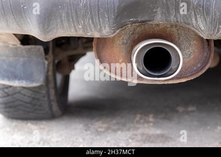 Rostige, staubige Auspuffrohre des Fahrzeugs vor einem unscharfen Hintergrund des Hinterrads. Nahaufnahme. Selektiver Fokus Stockfoto