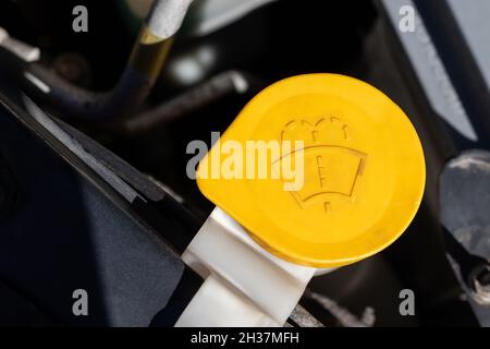 Windschutzscheibenwaschanlagendeckel. Gelbes Detail eines Motorraums unter der offenen Haube. Nahaufnahme an einem sonnigen Tag Stockfoto