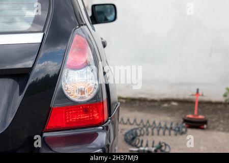 Rücklicht eines schwarzen Autos auf dem Reifenservice. Selektiver Fokus. Nahaufnahme Stockfoto