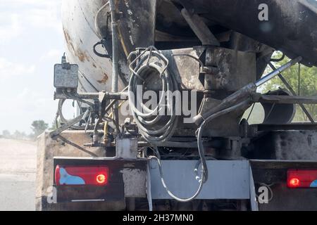 Betonmischwagen Rückansicht mit Schläuchen und brennenden Schlussleuchten bei Straßenarbeiten auf einer Überlandstraße. Nahaufnahme Stockfoto