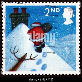 GROSSBRITANNIEN - UM 2004: Eine in Großbritannien gedruckte Briefmarke zeigt den Weihnachtsmann, der im Schnee zum Schornstein läuft, Weihnachten, um 2004 Stockfoto