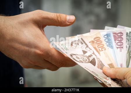 Geld aus Nordkorea, das einer anderen Person von Hand zu Hand gegeben wird Stockfoto