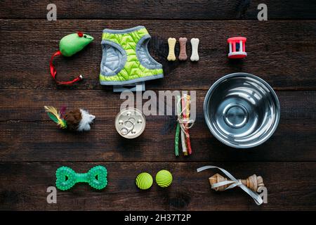 Tierpflege. Viele Lebensmittel, Spielzeug und Zubehör für Hund und Katze auf Holzgrund. Verschiedene Kugeln, Spielzeugmaus, Knochen zum Spielen und Training Stockfoto