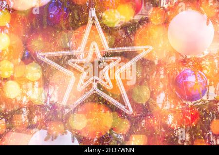 Großer Stern und Spielzeugkugeln auf dem Weihnachtsbaum auf der Straße auf einem verschwommenen und funkelnden Hintergrund. Vorbereitung auf die Weihnachtsferien. Stockfoto