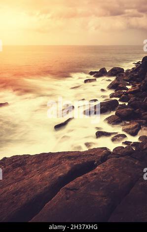 Felsiger Strand bei Sonnenuntergang, Farbtonung angewendet, Sri Lanka. Stockfoto