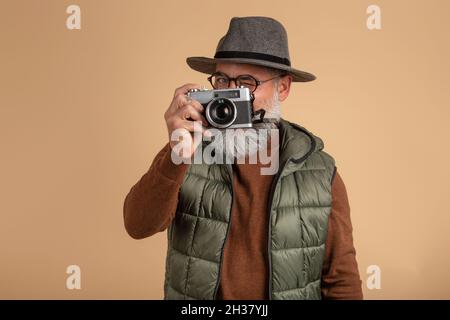 Hipster Touristenfotograf, der isoliert auf hellem Hintergrund mit Kamera steht Stockfoto