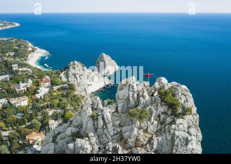 Luftaufnahme eines Mannes Touristen in roter Jacke, der auf der Felsenspitze des Katzenbergs steht und die Landschaft der Gegend von Simeiz genießt. Krim Stockfoto