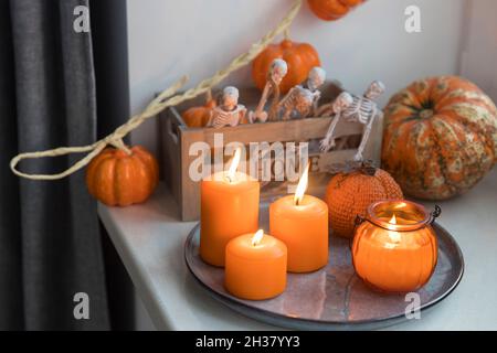 Porzellan und natürliche Kürbisse, orangefarbene Kerzen auf einem weißen Tisch, Halloween-Dekorationen. Stockfoto