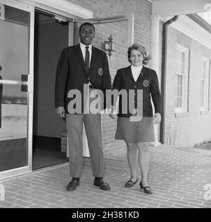 1967, historisch, ein schwarzer männlicher Sudent und eine weiße Studentin, die ihre College-Blazer mit Logos trägt und die Hände an der Tür zu den Klassenzimmern in Virginia, USA, hält. Sie sind Mitglieder des Studentenrates der Hochschule. In dieser Zeit war das Tragen von Blazern sowohl für Mädchen als auch für Jungen in der High School und Hochschule alltäglich, da Bildung immer noch eine einigermaßen formale, traditionelle Welt war. Boyswere sollte weiße Hemden mit Krawatte unter dem Blazer und den Mädchen, einen Blazer und Rock tragen. Stockfoto