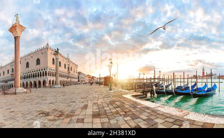 Möwe fliegt am Dogenpalast und Gondeln-Pier in der Nähe des Markusplatzes in Venedig, Italien, vorbei. Stockfoto