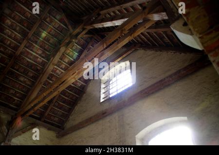 Vergessener Dachboden. Sonnenlicht, das aus einem Fenster in einem alten Gebäude scheint. Verlassene Innenausstattung mit Holzbalken. Stockfoto