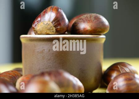 portugiesische Nüsse in Keramikbehälter auf Tisch mit gelber Jute Stockfoto