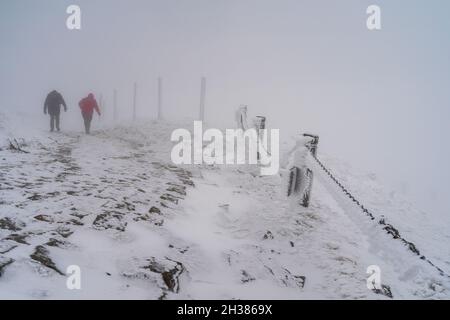 Winterstraße bergauf bei schlechtem Wetter. Reisende klettern die Straße bergauf. Stockfoto
