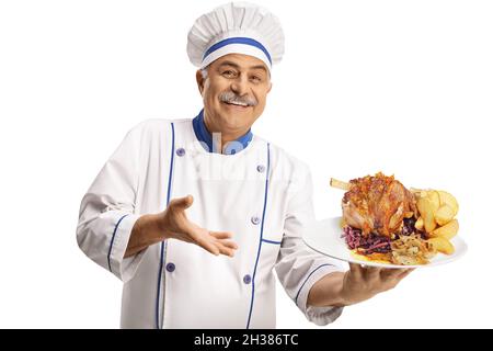 Fröhlicher reifer Koch lächelt und hält einen Teller mit einem Fleischgericht und Kartoffeln auf weißem Hintergrund isoliert Stockfoto