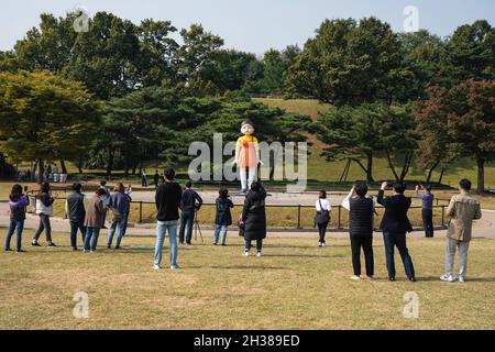 Seoul, Südkorea. Oktober 2021. Die Menschen fotografieren die riesige Puppe aus der Originalserie „Squid Game“ von Netflix im Olympiapark in Seoul. Die riesige Puppe aus der Originalserie „Squid Game“ von Netflix wird vom 25. Oktober bis 23. Januar nächsten Jahres im Olympic Park in Seoul, Südkorea, ausgestellt. Kredit: SOPA Images Limited/Alamy Live Nachrichten Stockfoto