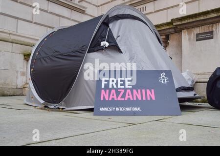 London, Großbritannien. Oktober 2021. Ein Plakat von Amnesty International "Free Nazanin", das während des Hungerstreiks neben einem Zelt zu sehen ist.Richard Ratcliffe, der Ehemann des britisch-iranischen Hilfsarbeiters Nazanin Zaghari-Ratcliffe, setzt seinen Hungerstreik vor dem Außenministerium in Whitehall fort und fordert die britische Regierung auf, mehr zu tun, um bei ihrer Freilassung zu helfen. Nazanin Zaghari-Ratcliffe ist seit 2016 im Iran inhaftiert, weil er angeblich Propaganda gegen die iranische Regierung verbreitet hat. Kredit: SOPA Images Limited/Alamy Live Nachrichten Stockfoto