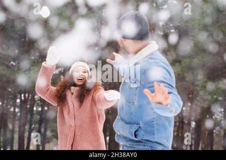 Glückliches junges Paar, das am Wintertag Spaß im Wald hat Stockfoto