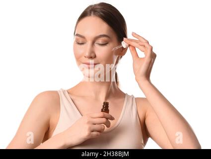 Frau mit geschlossenen Augen, die Öl mit Pipette ins Gesicht tropft Stockfoto