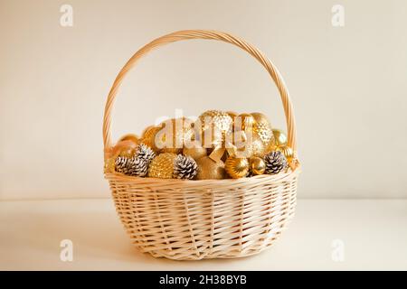 Riesiger Korbkorb, gefüllt bis an die Spitze mit goldenen Kugeln, um Weihnachtstanne oder Wohnung zu schmücken Stockfoto