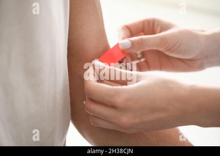 Arzt, der in der Klinik einen medizinischen Pflaster auf den Arm des Patienten aufsetzt, Nahaufnahme Stockfoto