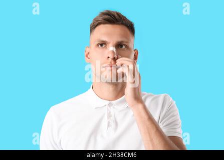 Mann mit medizinischem Fleck auf der Nase vor farbigem Hintergrund Stockfoto