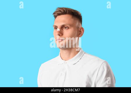 Mann mit medizinischem Fleck auf der Nase vor farbigem Hintergrund Stockfoto