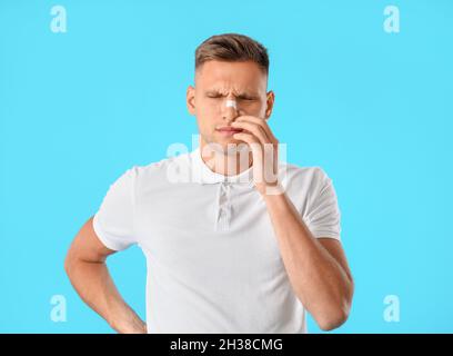 Mann mit medizinischem Fleck auf der Nase vor farbigem Hintergrund Stockfoto