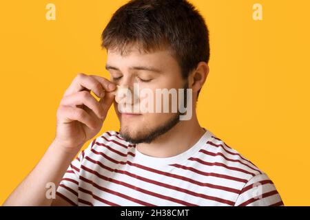 Mann, der vor farbigem Hintergrund medizinische Pflaster von seiner Nase entfernt Stockfoto