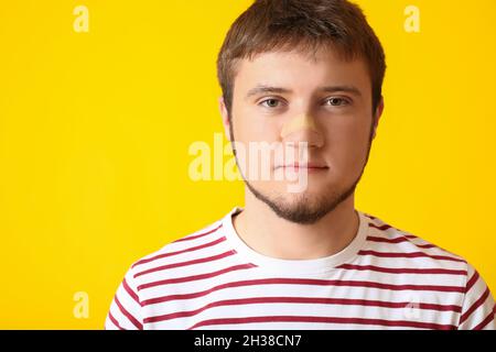 Mann mit medizinischem Fleck auf der Nase vor farbigem Hintergrund Stockfoto