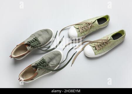 Zwei Paar stylische Schuhe mit ungebundenen Schnürsenkeln auf weißem Hintergrund Stockfoto