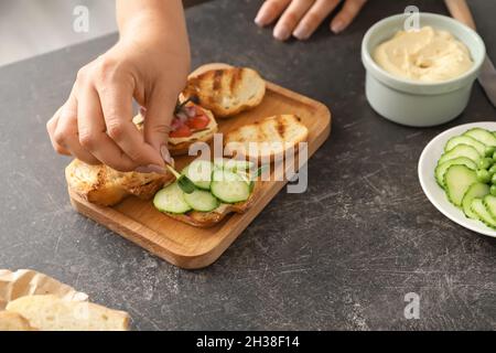 Frau kocht leckere vegetarische Bruschettas am Tisch in der Küche, Nahaufnahme Stockfoto