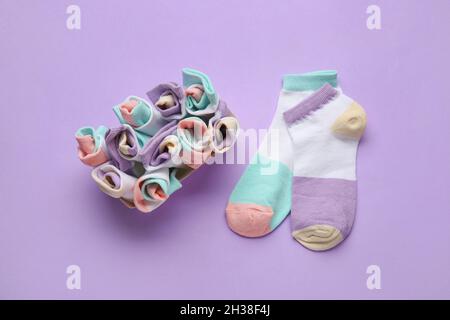 Box mit vielen verschiedenen Socken auf farbigem Hintergrund Stockfoto