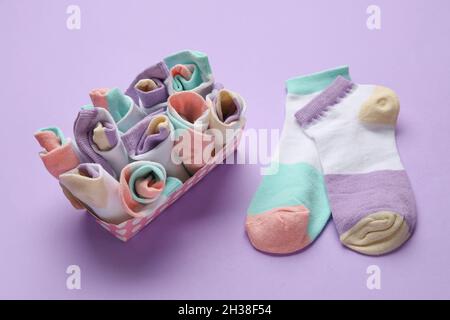 Box mit vielen verschiedenen Socken auf farbigem Hintergrund Stockfoto