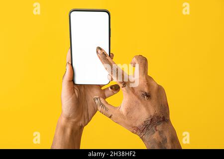 Hände von Zombie mit Handy auf farbigem Hintergrund Stockfoto