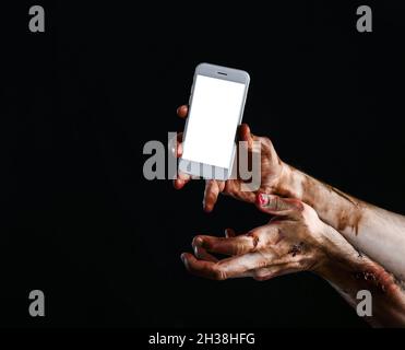 Hände von Zombie mit Handy auf dunklem Hintergrund Stockfoto