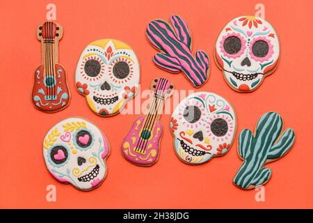 Cookies in Form von Totenköpfen, Gitarren und Kakteen auf rotem Hintergrund. El Dia de Muertos Stockfoto