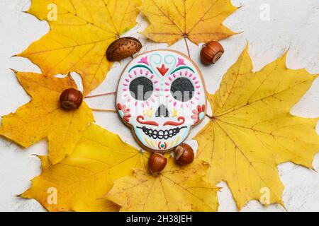 Schädelförmiges Keks für Mexikos Tag der Toten (El Dia de Muertos) mit Nüssen und gefallenen Blättern auf weißem Hintergrund Stockfoto