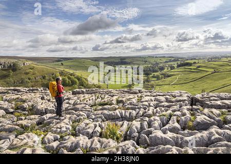 Person, die auf den Rändern und Grykes auf Malham Cove, Yorkshire Dales, Großbritannien, steht Stockfoto