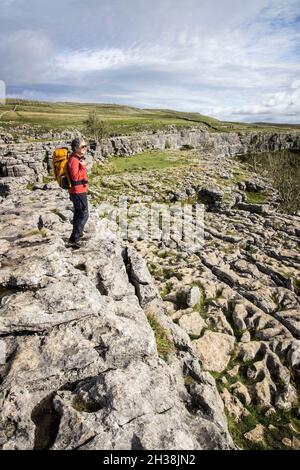 Person, die auf den Rändern und Grykes auf Malham Cove, Yorkshire Dales, Großbritannien, steht Stockfoto