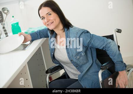 Junge Frau im Rollstuhl, die Arbeit verrichten und lächeln Stockfoto