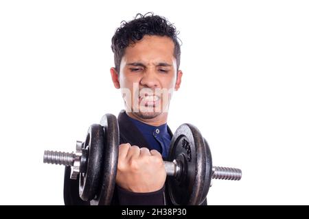 Schlanker Mann Gewichte heben auf weißem Hintergrund. Junger latein, der schwer Gewicht hebt. Schwacher und lustiger Mann, der viel Kraft tut. Stockfoto