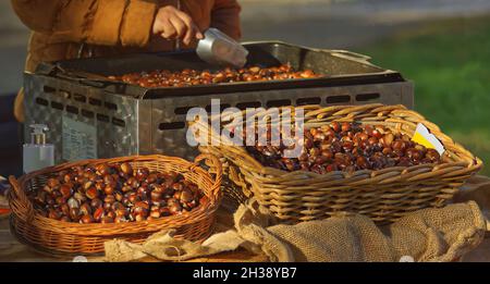 Ein Korbkörbchen mit einem Haufen essbarer Kastanien auf einem Bauernmarkt. Auch bekannt als Edelkastanie oder castanea sativa und spanische Kastanie. Stockfoto