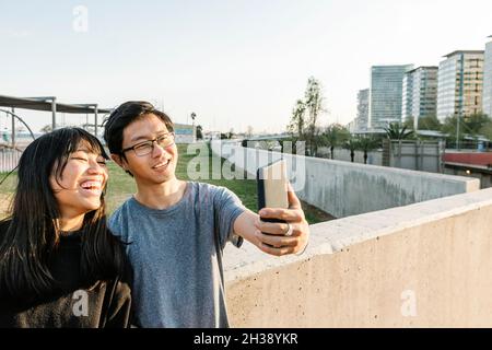 Glückliche asiatische Freunde, die Spaß haben, während sie Selfie mit dem Smartphone im Freien machen Stockfoto