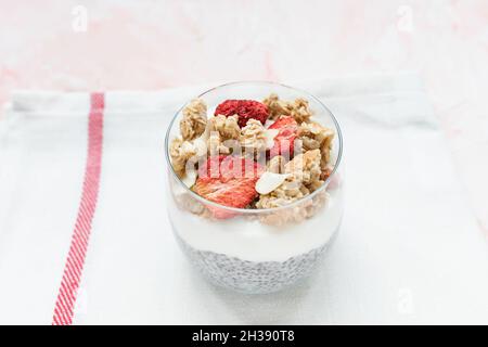 Über Nacht Chiasamen-Parfait-Pudding mit Mandelmilch, Joghurt, hausgemachtem Müsli, getrockneten Erdbeeren und Mandeln in einem Glas. Superfood und veganes Lebensmittelkonzept. Kopierbereich, selektiver Fokus Stockfoto