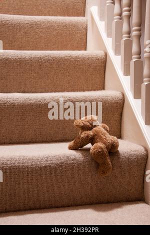 Niedlicher Teddybär, der die Treppe zum Bett klettert Stockfoto